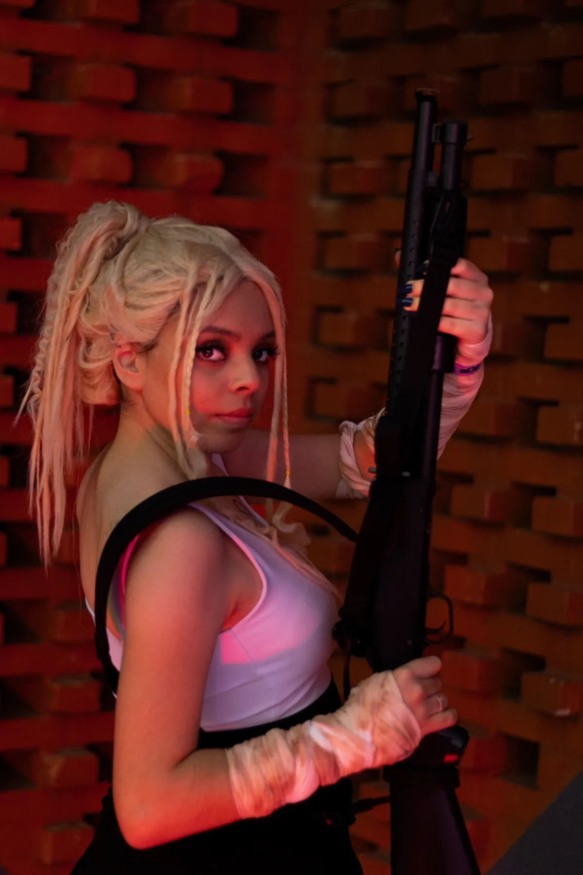 Cosplayer de cabelo claro posa diante de uma parede de tijolos